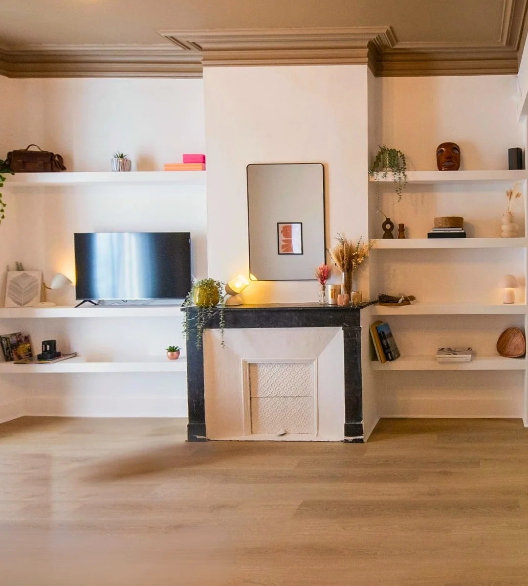 Salon après travaux de rénovation : cheminée en marbre noir et bibliothèque sur mesure, appartement haussmannien à Montpellier