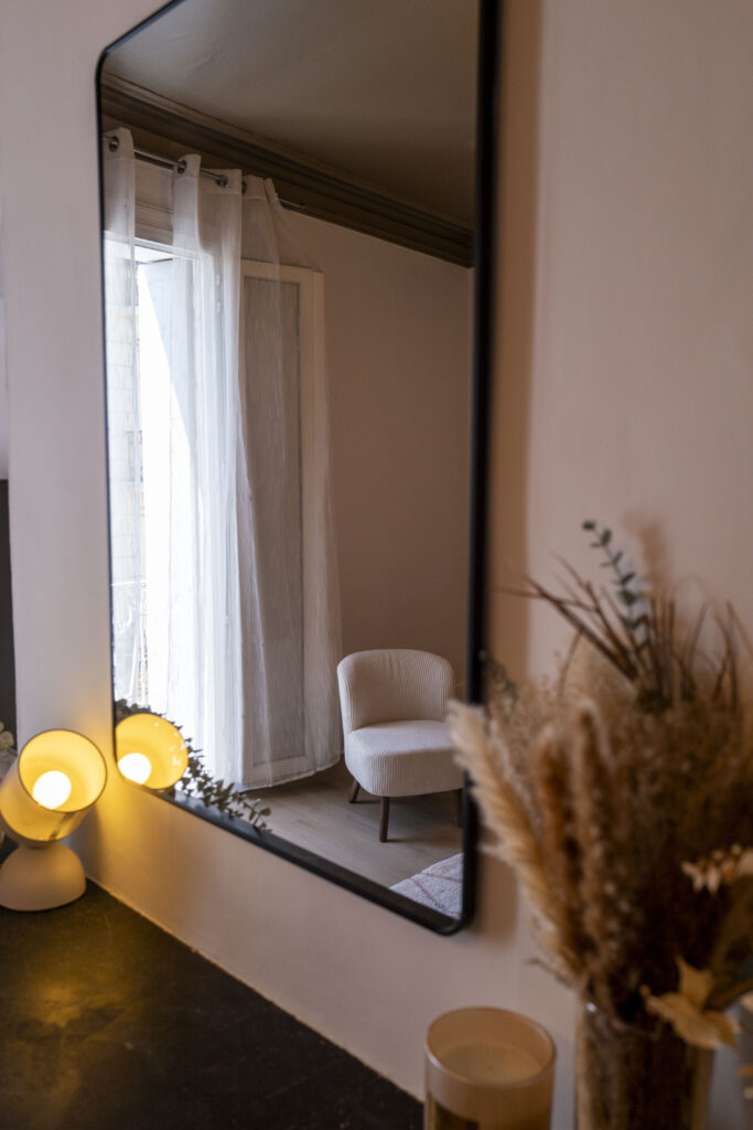 Grand miroir reflétant le salon lumineux et ses voilages
