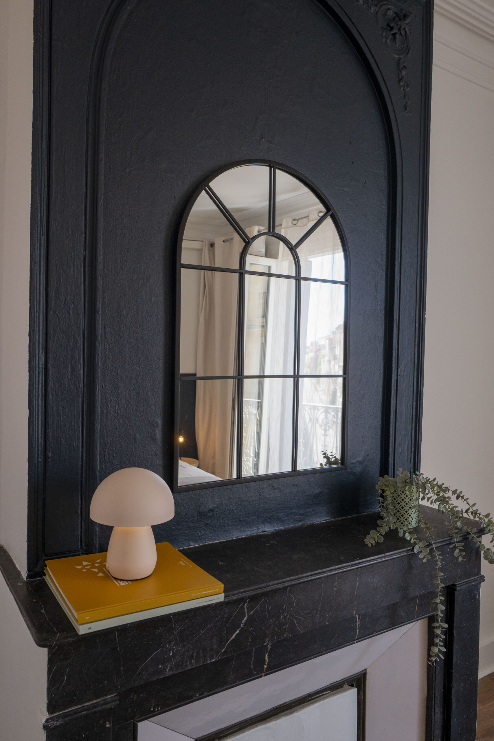 Trumeau en arche repeint en noir avec miroir et cheminée en marbre dans une chambre après rénovation, Montpellier
